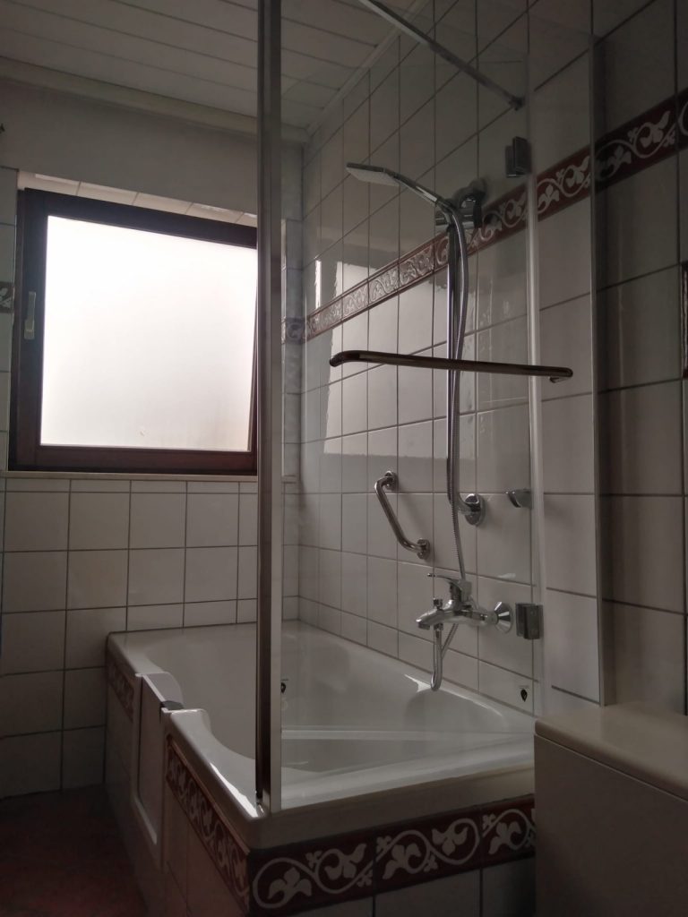 Moderne Badewanne mit Badewannentür und Duschbereich in einem hellen Badezimmer. - Praktisches Bad
