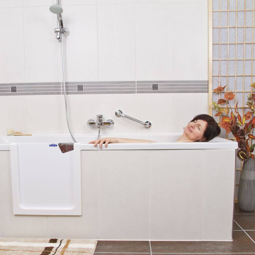Eine Frau entspannt in einer Badewanne mit einem barrierefreien Einstieg, umgeben von einer modernen Badezimmerumgebung. - Praktisches Bad